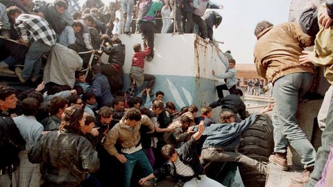Albaneses intentando subirse a un barco de pesca para abordar a una fragata griega, en un intento fallido de llegar a Grecia