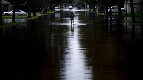 Una mujer camina por un camino inundado durante las secuelas del huracn Harvey