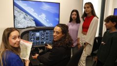 Un grupo de estudiantes con una de las profesoras que les enseña el funcionamiento del simulador de vuelo