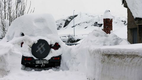 Un vehculo cubierto de nieve, en el pueblo asturiano de Pajares.