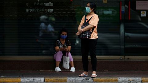 Mujeres con mascarillas protectoras esperan un autobs en Bangkok