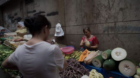 Una clienta compra verduras en una calle de la ciudad china de Chongqing.