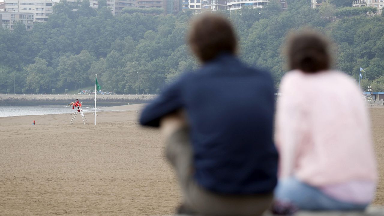 Una pareja observa la playa vizcana de Erega, sin baistas como consecuencia del mal tiempo en la cornisa cantbrica