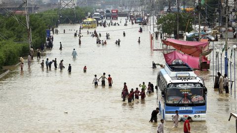 Varias personas caminan por las calles inundadas del centro de Karachi tras las inundaciones del monzn