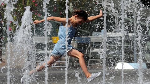 Una nia salta en una fuente de agua en el centro de Viena