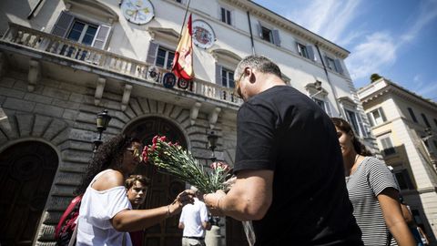 Varias personas prepararan flores para colocarlas en la puerta de la embajada española en la Santa Sede en Roma