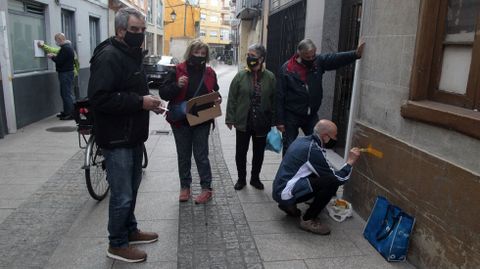 Voluntarios de una asociación de amigos del Camino de Invierno pinta flechas amarillas a su paso por Monforte