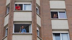 Varios vecinos aplauden la actuación del músico Miguel Gallego, que toca el saxo desde la ventana de su domicilio en Gijón,
