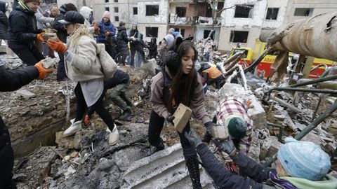 Voluntarios retiran los cascotes de un edificio bombardeado en Kiev.