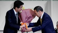 Shinzo Abe entrega un ramo de flores a su sucesor Yoshihide Suga