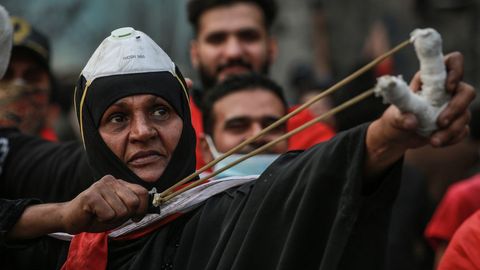 Una  mujer usa un tirachinas contra las fuerzas del orden en la calle Al Rasheed de Bagdad