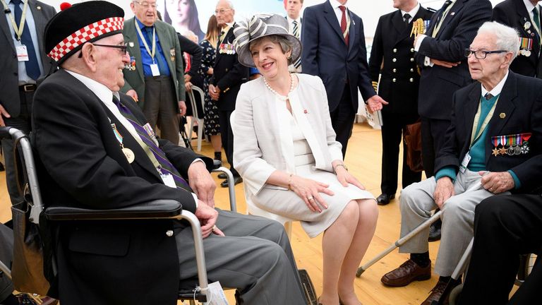 May charla con veteranos en durante una ceremonia en el cementerio de la Commonwealth con motivo del 75º aniversario del desembarco de Normandía