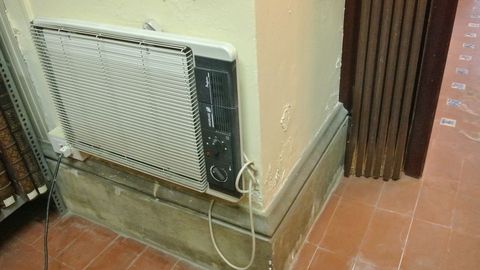 Un viejo radiador elétrico colgado de una pared dañada 