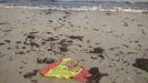 Bandera de España arrastrada por la marea, en la playa de San Lorenzo de Gijón