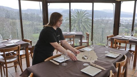 Dolores prepara una mesa del comedor acristalado, con vistas a Cedeira y a la ría