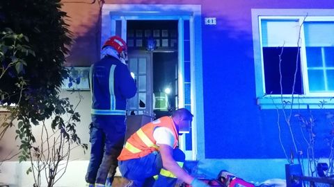 Servicios de emergencias actuando en la puerta de la vivienda donde se produjo el incendio, en Lira