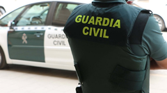 Un agente de la Guardia Civil, de espaldas, junto a un vehculo oficial