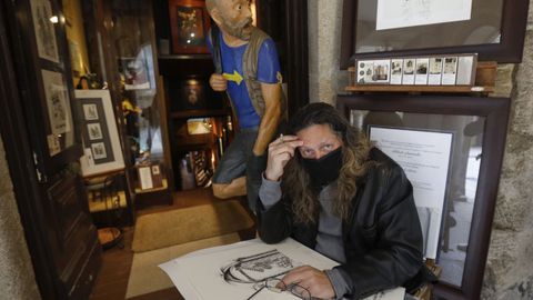 El ilustrador, humorista grfico y comunicador Juan Carlos Zamora muestra sus obras ante su conocida tienda de la ra Nova. Tras l, salta a la vista la figura del fotografiado  Seferino. Es mi peregrino divino, de ah su nombre. Yo lo escribo con ''s'' por mi seseo, apunta divertido el creador colombiano