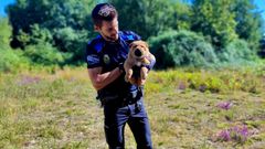 El agente de la Polica Local de O Carballio, con el perro, de raza Sharpei, rescatado.