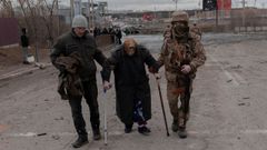 Un civil y un soldado ayudan a una mujer mayor a salir de Irpin, en la regin de Kiev