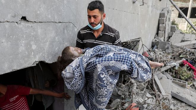 Un hombre, portando el cadver de una nia fallecida en el bombardeo israel de su casa en Nuseirat, en la Franja