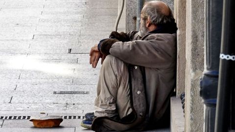 Un hombre sin techo pidiendo en una calle de Vigo