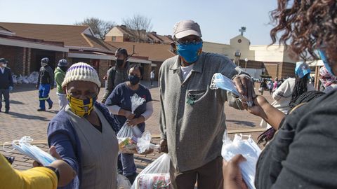 Ciudadanos con mascarilla reciben ayuda durante la pandemia en Soweto, Sudfrica
