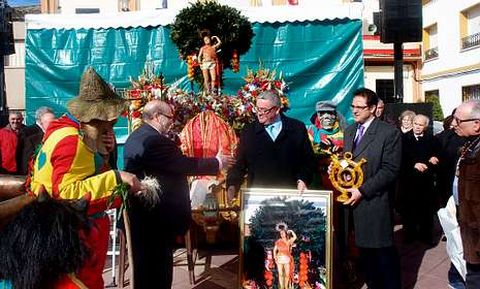 Alfredo Caizo recibe el saludo del presidente de la Cofrada de San Sebastin ante la mirada del alcalde de Malpica de Tajo, los vecinos y algunos de los personajes tradicionales de sus fiestas.