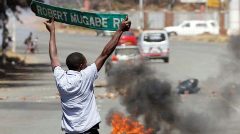 Un hombre alza una seal de trfico mientras se producen choques partidarios de la oposicin y los policas en Zimbabue.