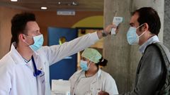 Un sanitario mide la temperatura a un hombre que accede al hospital de Alcorcn, en Madrid