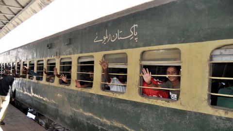 Pescadores indios arrestados por violar las aguas territoriales saludan desde un tren tras ser liberados por las autoridades paquistanes