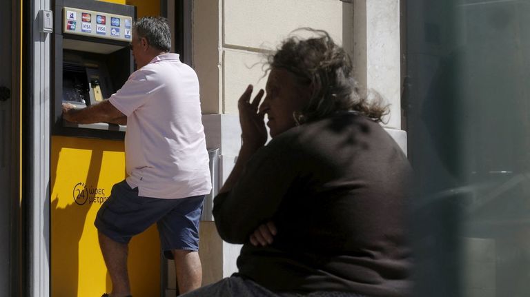Un hombre saca dinero de un cajero de Piraeus Bank, en Atenas, en julio del 2015