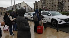 Viajeros esperando bajo la lluvia para coger un taxi