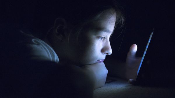 Una menor consume contenidos digitales desde un tel�fono m�vil, en una imagen de archivo