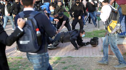 Un policía nacional por los suelos durante las cargas que se han registrado en protesta por el acto de precampaña de Vox