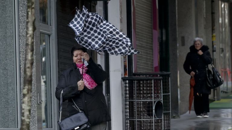 Una mujer y su paraguas pelean contra el viento esta mañana en A Coruña