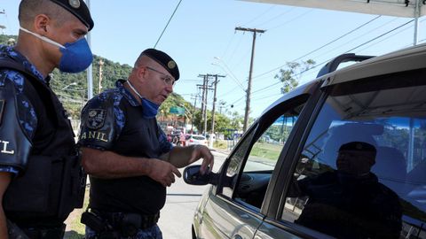 Oficiales de Polica registran a un viajero en la entrada de la ciudad, en medio de la crisis del coronavirus en Sao Paulo, Brasil