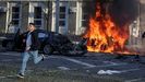 Imagen de archivo de un hombre corriendo por una calle del centro de Kiev mientras a su espalda arde un coche alcanzado por un proyectil ruso.