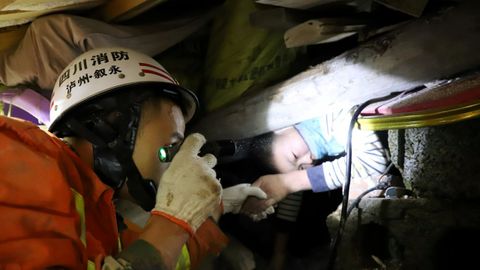 Un bombero ayuda a un nio atrapado entre escombros tras un deslizamiento de tierra en Xuyong, China