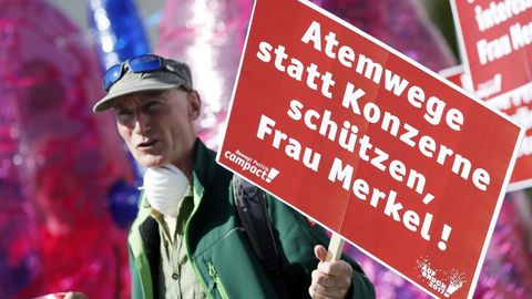 Protesta este mes en Berln en el que un manifestante porta una pancarta con el lema: Seora Merkel: protega las vas respiratorias en lugares de a las grandes corporaciones.