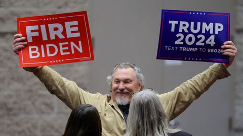 Un seguidor de Donald Trump levanta carteles electorales del expresidente en Wisconsin.