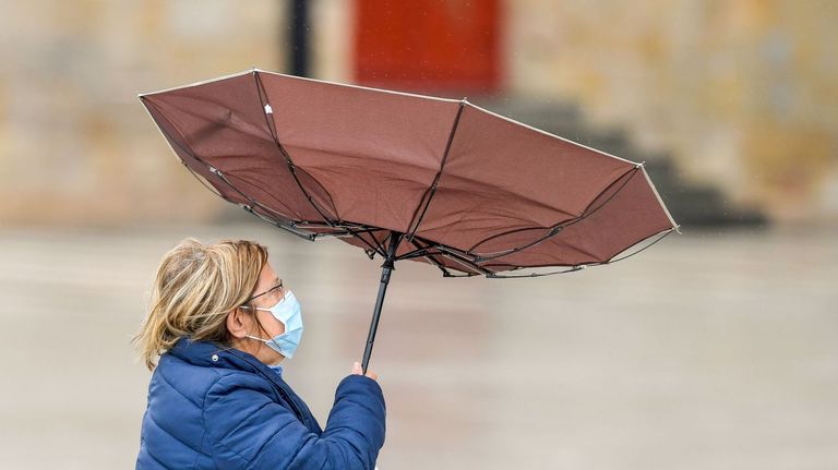 Una mujer camina en un día de lluvia y viento por Gijón