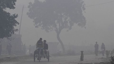 Un hombre indio monta en un triciclo en una maana cubierta de niebla en las afueras de Nueva Delhi
