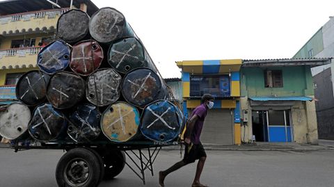 Un hombre con mascarilla tira de un carro en Colombo, Sri Lanka
