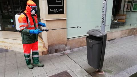 Un trabajador de Emulsa desinfecta una papelera, en una calle de Gijn