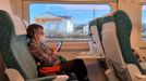 Una viajera del Alvia Vigo-Barcelona, entretenida leyendo mientras el tren sale de Astorga