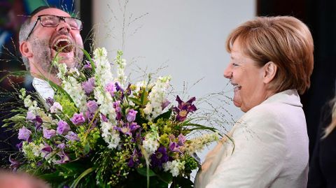 La canciller alemana Angela Merkel le entrega un ramo de flores al Ministro de Asuntos Exteriores Michael Roth por su cumpleaos