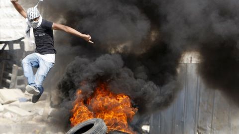 Un palestino evita el fuego en medio de los enfrentamientos con las fuerzas de Israel en la localidad palestina de Hebron