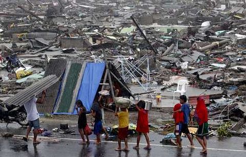 Niños filipinos llevan algunos enseres en la ciudad de Tacloban, la más afectada por el tifón «Haiyan»