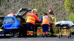 Momento en que sanitarios y bomberos sacan en camilla por la parte trasera del coche a una de las mujeres heridas en el accidente de A Pobra do Brolln